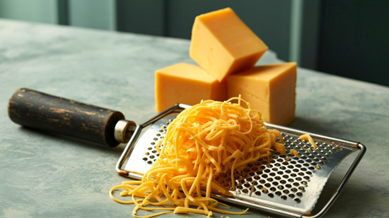 Blocks of cheddar cheese with a grater