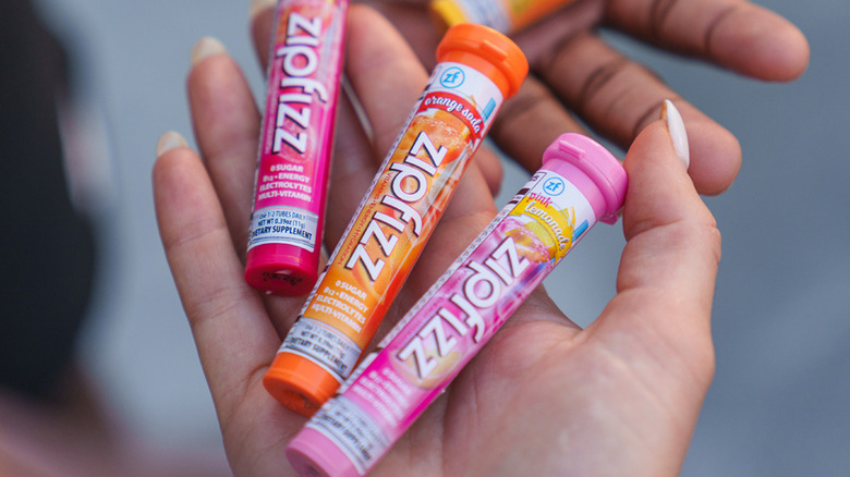 Hands holding various Zipfizz flavors