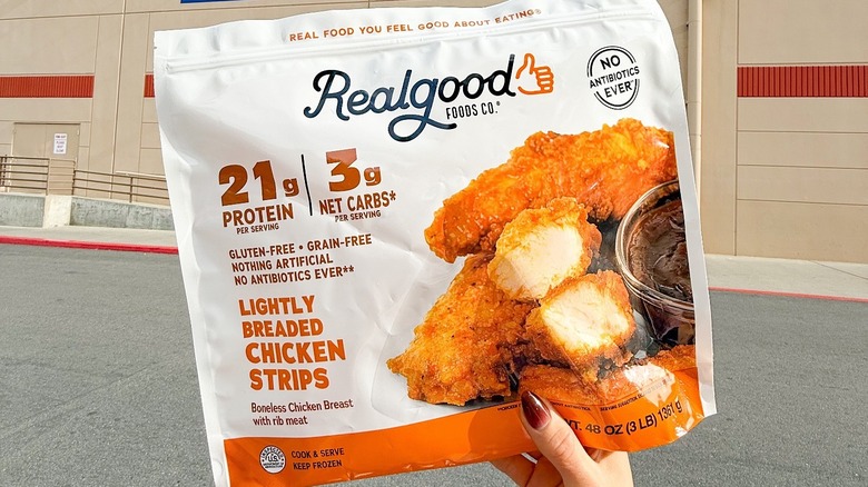 Hand holding Real Good Foods Chicken Strips in front of Costco