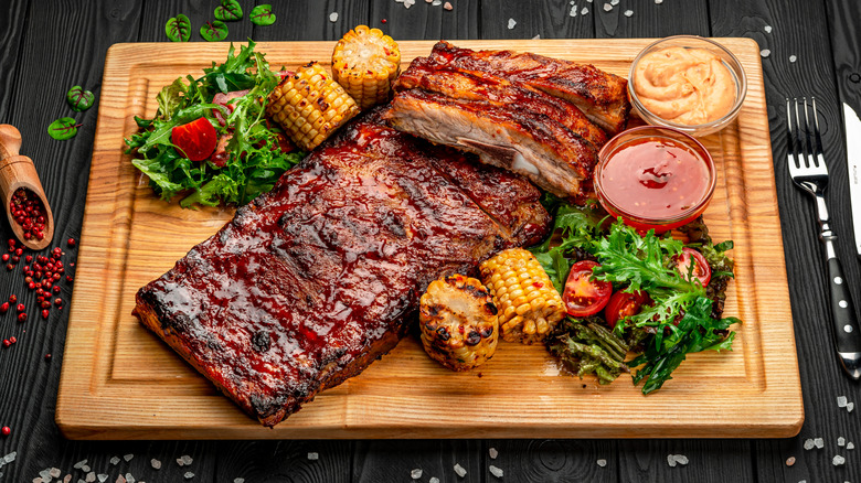 Ribs garnished with corn on the cob, salad and sauces