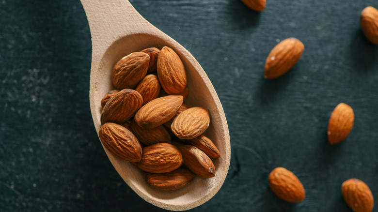 Spoonful of almonds and scattered almonds