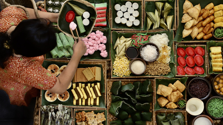 Overhead shot of a woman serving traditional Indonesian sweets in a market.