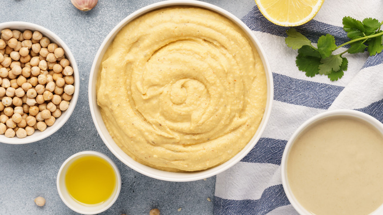 bowl of hummus, bowl of chickpeas, half lemon, lemon juice, parsley, bowl of tahini