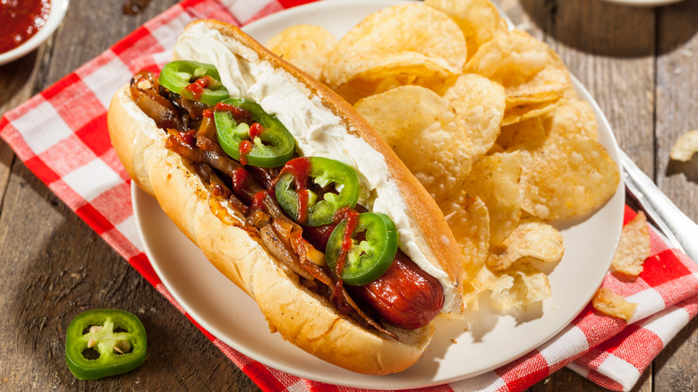 Seattle style hot dog on plate with chips