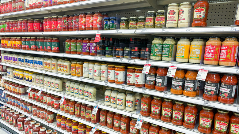 Shelves lined with various pasta sauces at a grocery store.