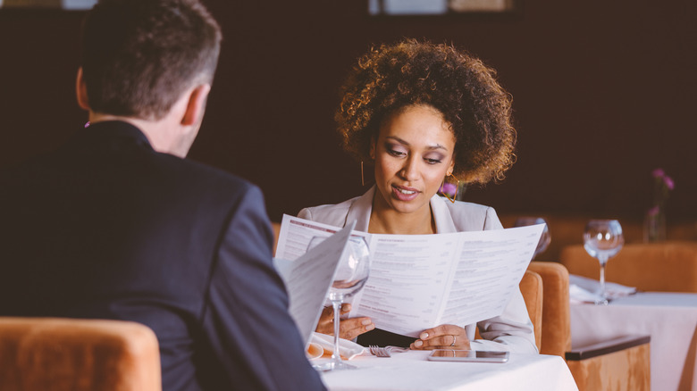 man and woman looking at menus