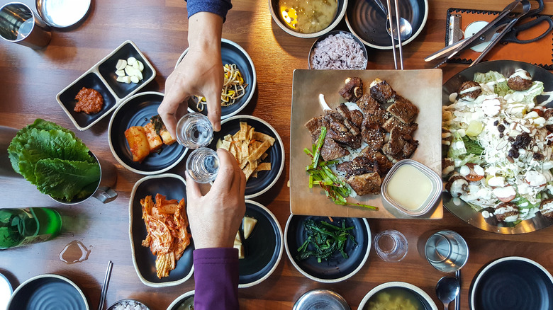 Two people toasting over spread of food