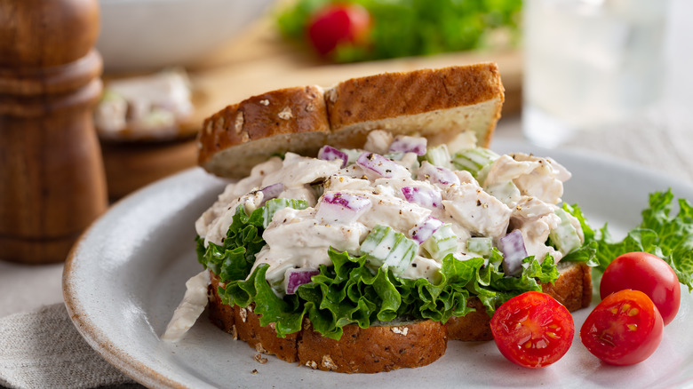 Chicken salad sandwich next to berries on a white plate.