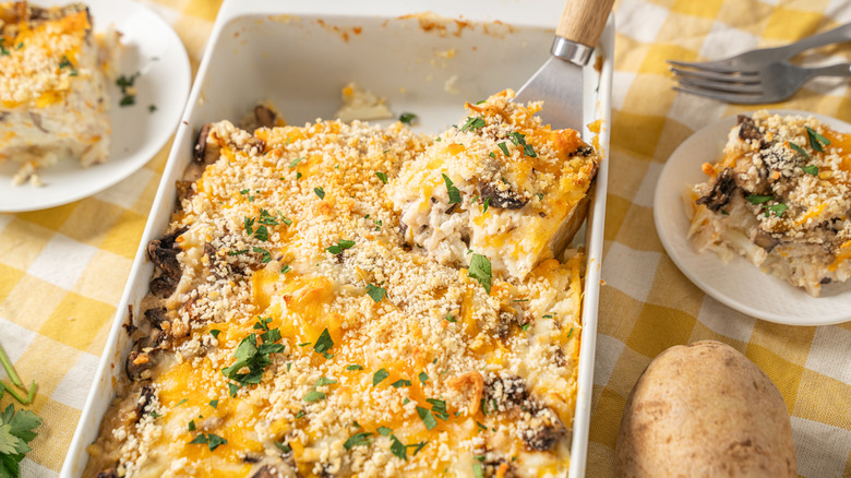 Someone scoops a crunchy casserole portion out of a pan