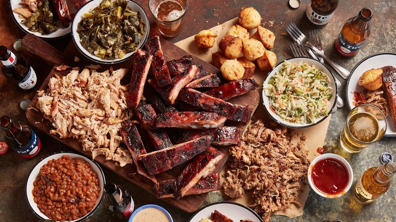 Smoked meats on a wooden cutting board with sauces.