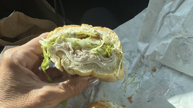 A hand holds a turkey sub from Jersey Mike's.