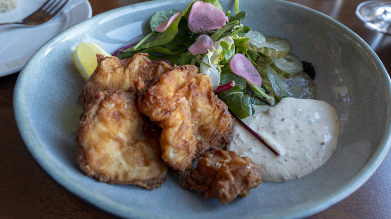 Fried cod tongue in a blue bowl with a salad and tartar sauce