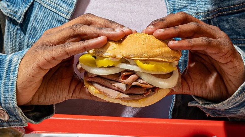 Someone holds a roast beef sandwich with two hands.