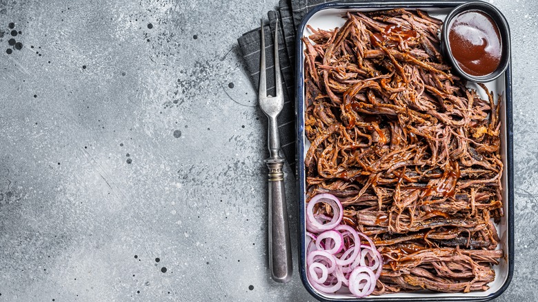 Pulled beef roast with red onions and barbecue sauce on a tray