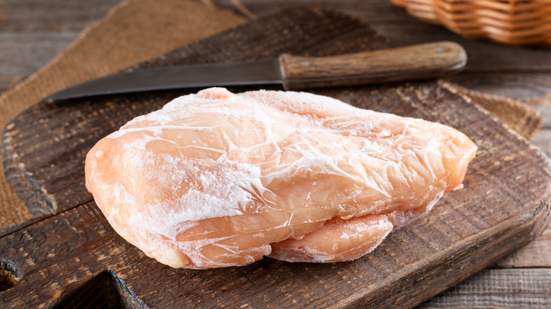 Frozen chicken breast on a wooden cutting board