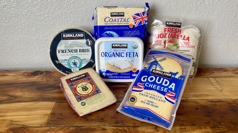 A variety of cheeses from Costco sit on a wooden surface.