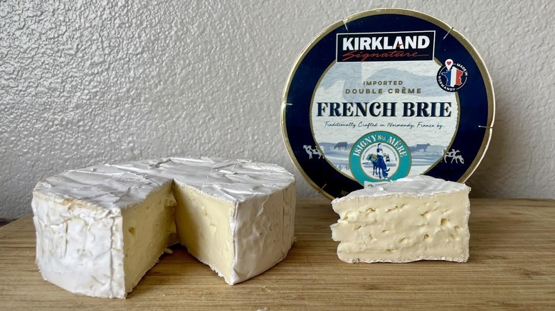 A wheel of brie cheese sits on a wooden surface.