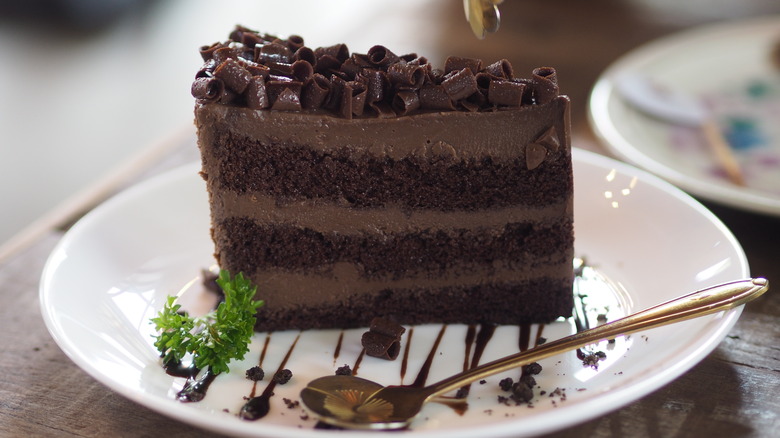 A layered chocolate cake with chocolate shavings and a chocolate drizzle