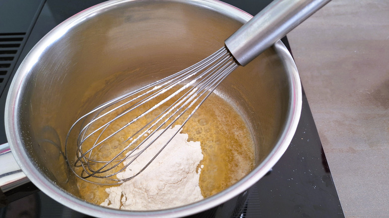 A person making a roux in a saucepan.