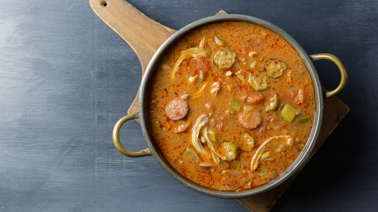 A pot of gumbo on a wooden paddle.