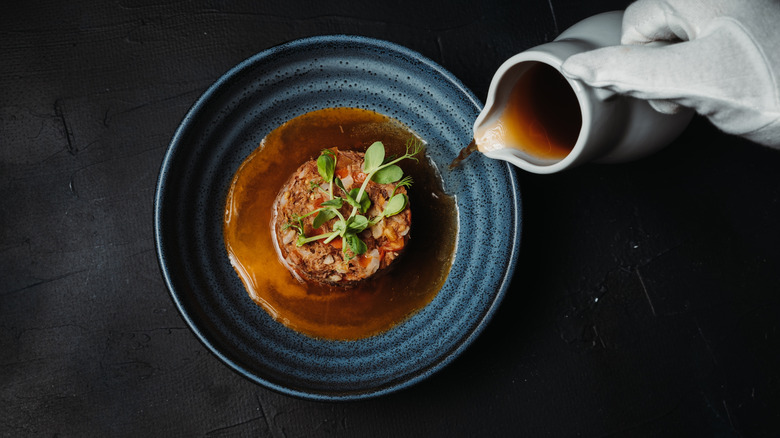 Broth poured over an elegant tartare dish.