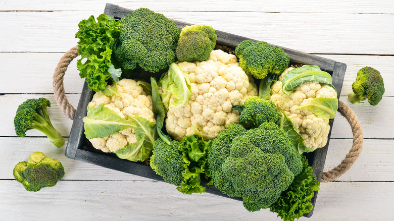 Whole heads of broccoli and cauliflower in a wooden produce box