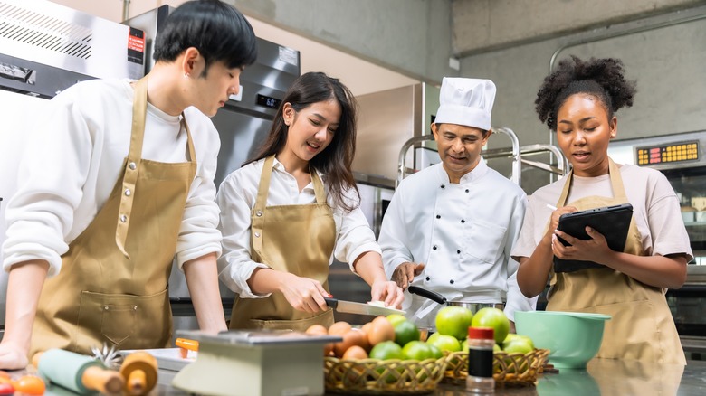 Students learning knife skills from a chef