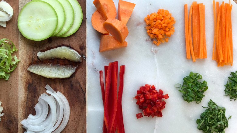 Herbs, vegetables, and fruits cut in different styles on a cutting board