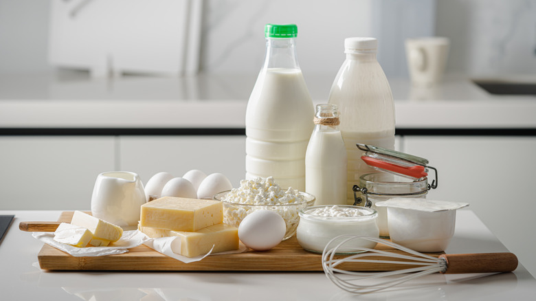 Ricotta and cottage cheese sit on a cutting board along with milk, eggs, and other items.