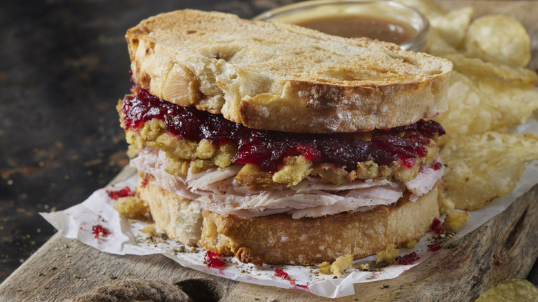 A sandwich made with toasted bread, cranberry sauce, and leftover turkey.