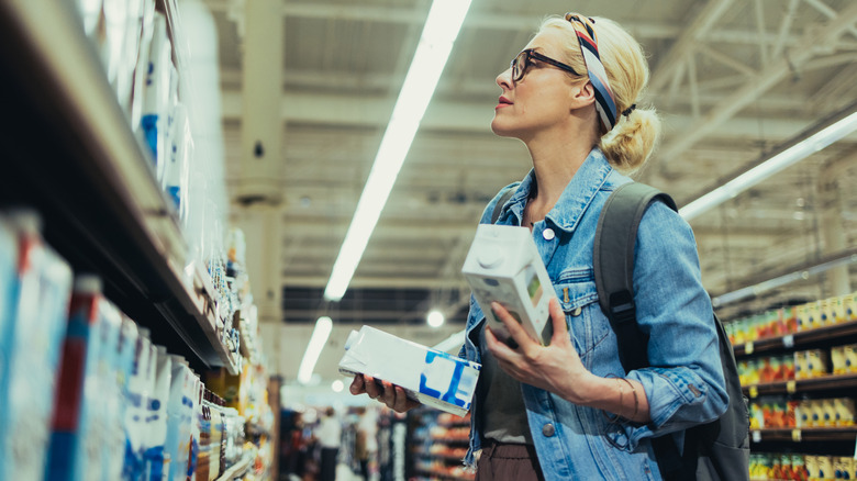A woman holds cartons of shelf-stable milk at a supermarket