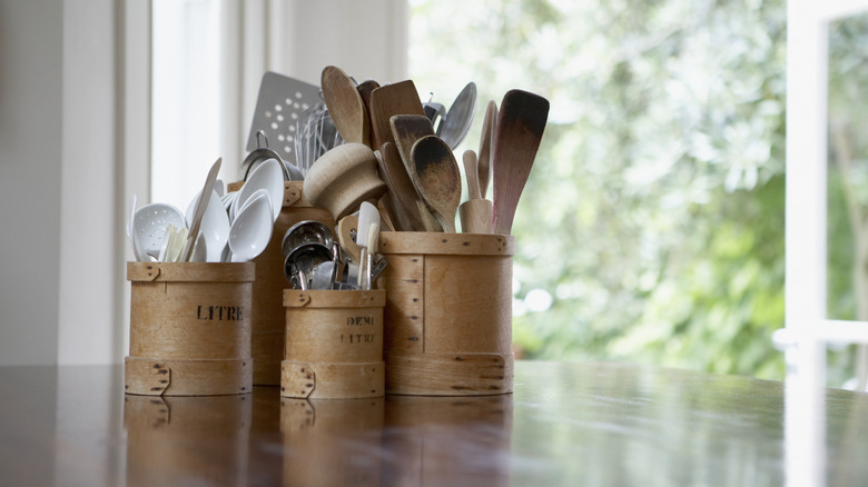 Cannisters sit on a kitchen counter, filled with utensils