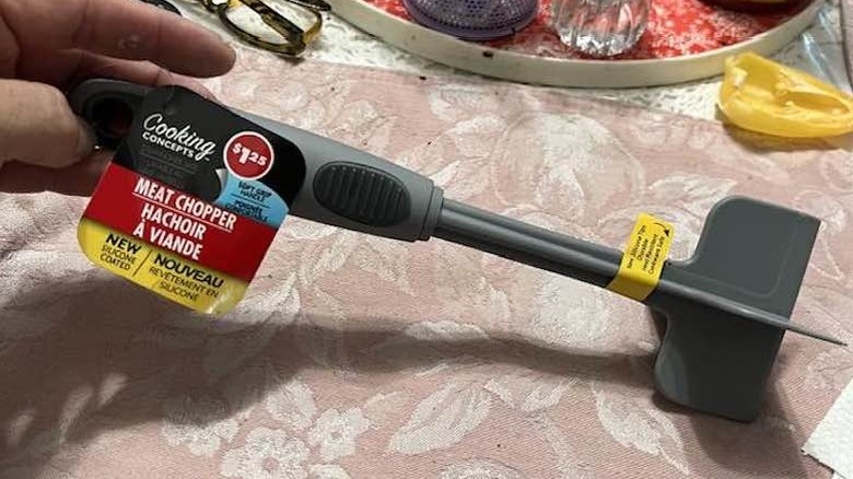 A hand holds a Dollar Tree meat chopper