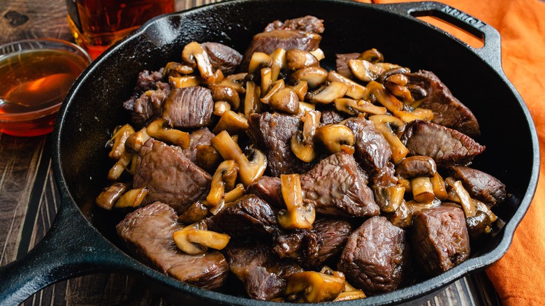 steak tips and mushrooms in cast iron skillet