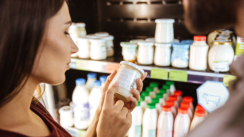 Woman checking yogurt expiration