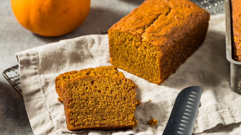 A loaf of pumpking bread sitting on a cloth to cool