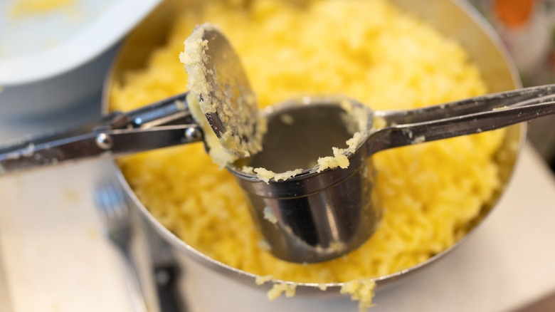 Using a potato ricer to mash boiled potatoes