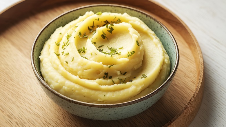 A bowl of creamy mashed potatoes topped with herbs