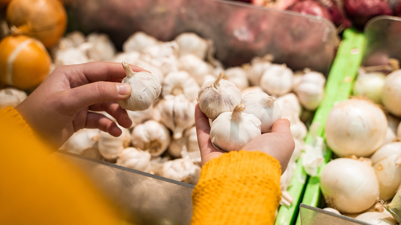 Close-up of female hand holding garlic at supermarket.