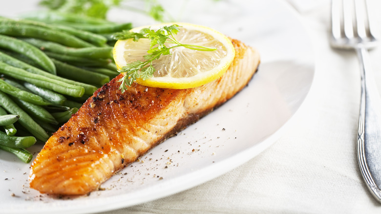 salmon served on a plate alongside green beans and lemons