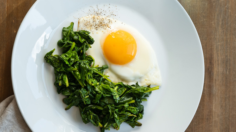 Sauteed spinach on a plate with a fried egg.