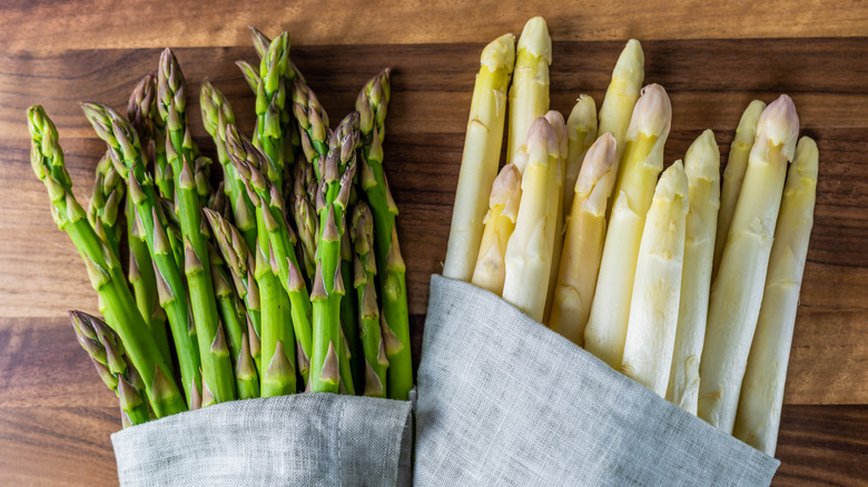 Two bunches of green and white raw asparagus wrapped in cloth