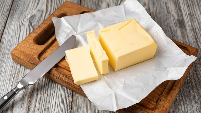 A sliced stick of butter in its wrapper atop a cutting board