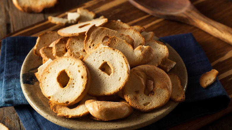 A pile of bagel chips on a rustic plate and wooden table