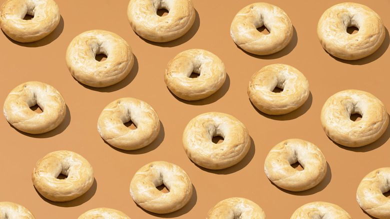 A whole table full of bagels laid out on a brown background