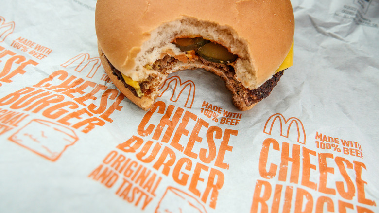 A McDonald's cheeseburger with a bite taken out of it sits on a wrapper