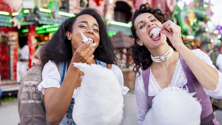 Two young women enjoying cotton candy at a carnival
