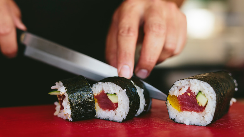 man slicing sushi roll