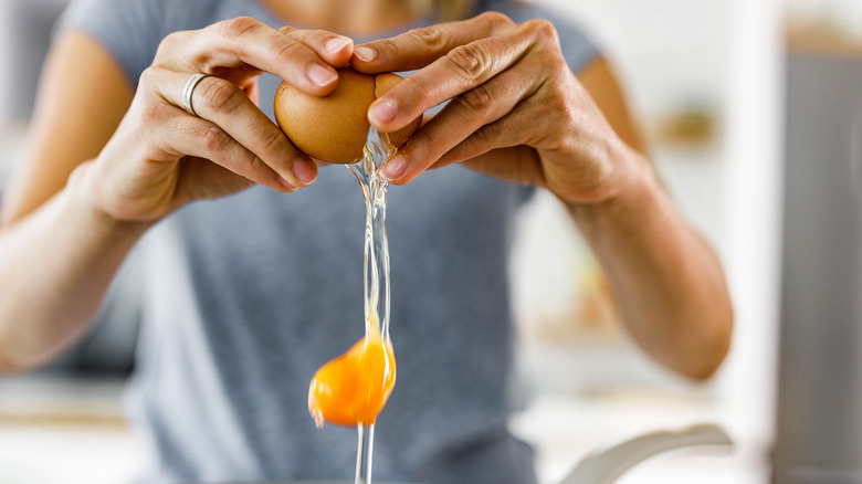 Close-up of hands cracking open an egg