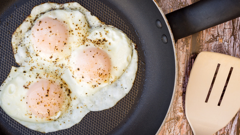 Over-easy fried eggs in pan with spatula